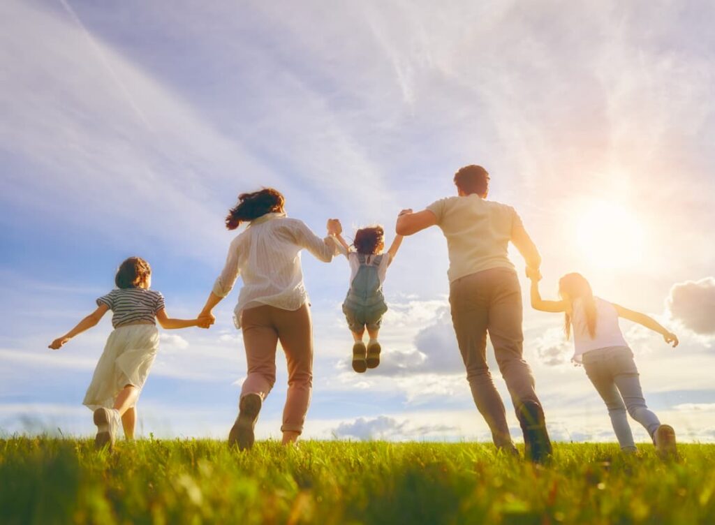 Top Austin TX Insurance Agency - Family Protection A happy family running through a sunny field in Austin, TX, representing the protection and peace of mind provided by life insurance from The Lambert Agency.