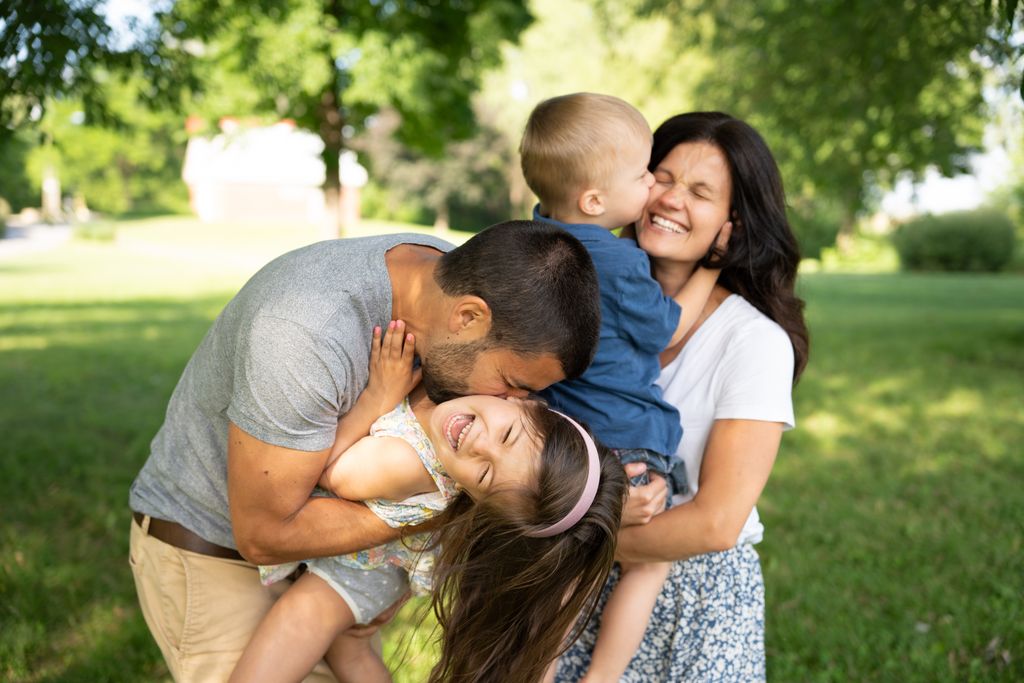 Joyful family enjoying a playful day in a lush green park.