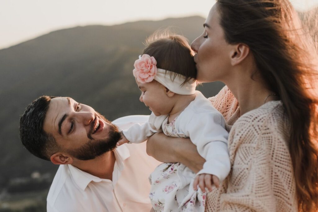 pexels-photo-5416649-5416649 A joyful family moment with parents and baby enjoying the outdoors at sunset.